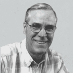 A black and white photo of an older man smiling.