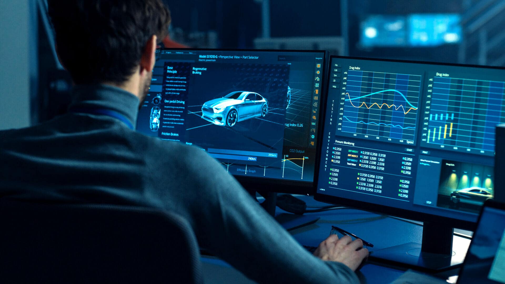 A man is sitting at a desk with two monitors in front of him.