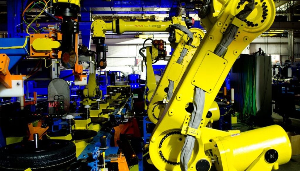 A factory with many yellow robots working in a factory.