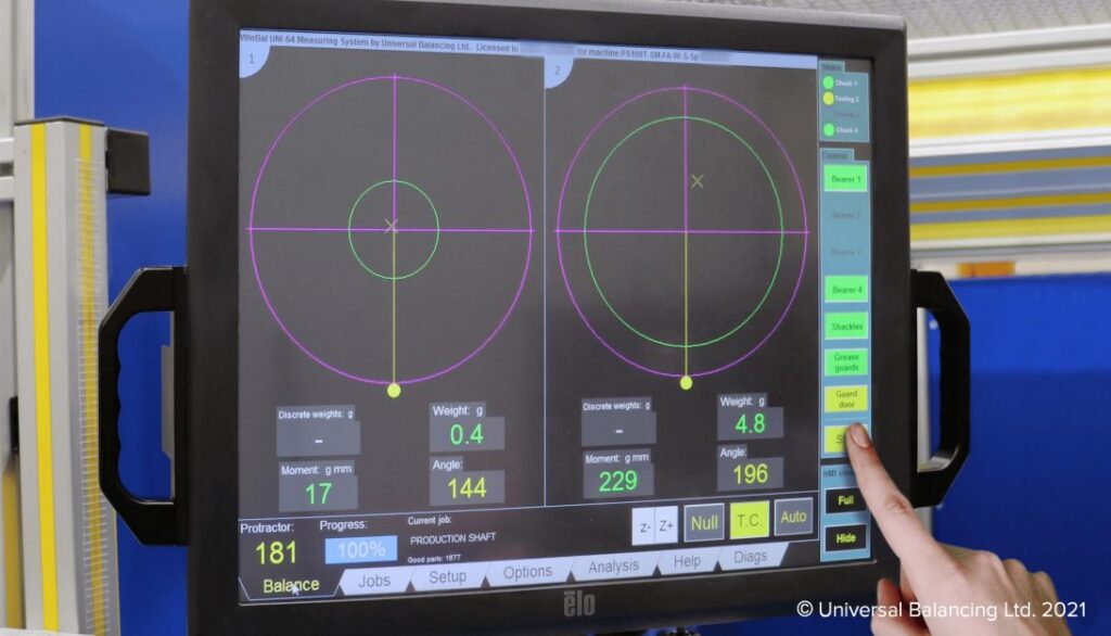 A person is pointing at a computer screen in a machine shop.