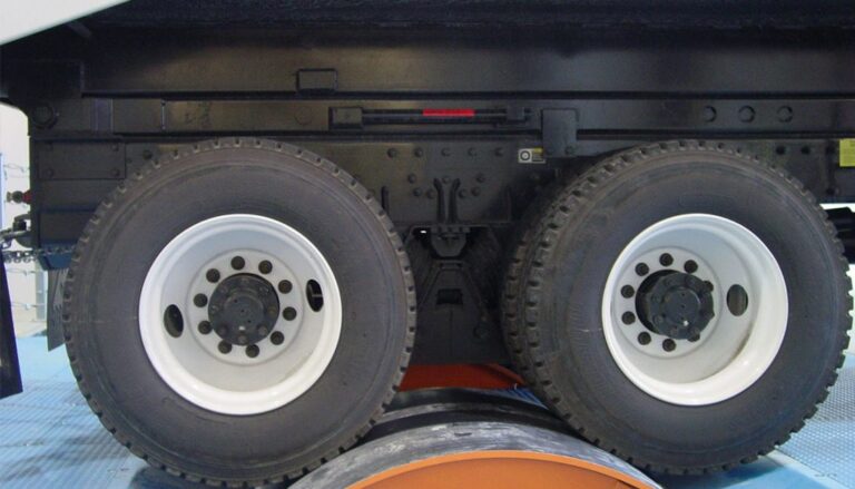 The wheels of a truck are on a conveyor belt.