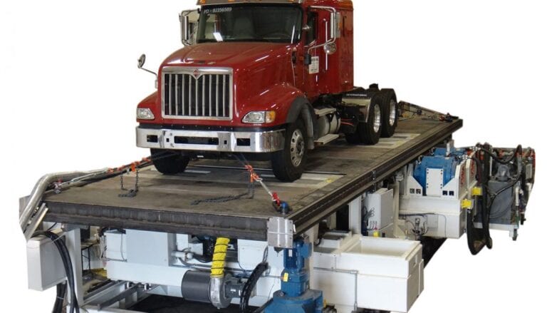 A truck on a flatbed truck lift.