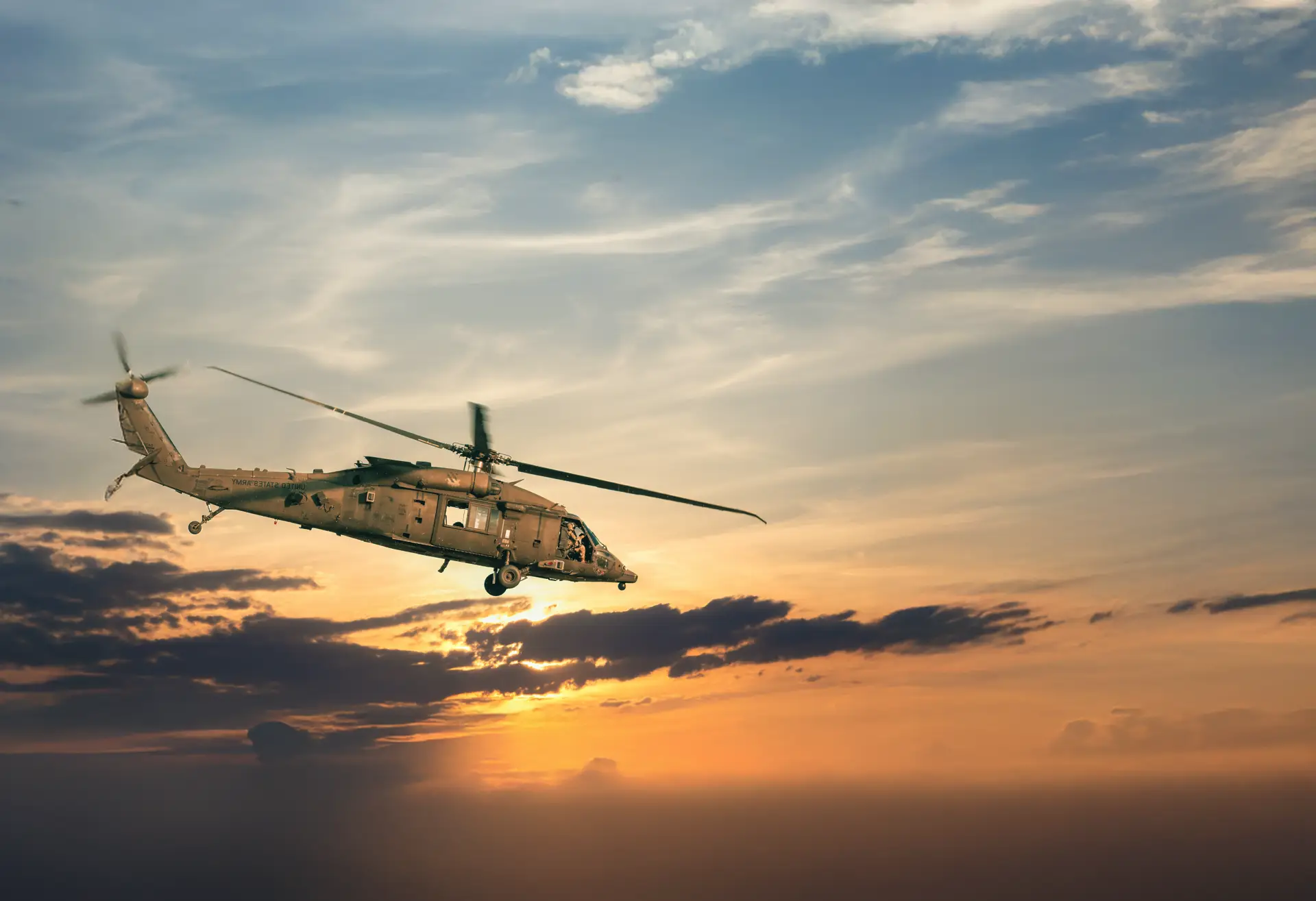 Helicopter flying against a sunset sky with scattered clouds.